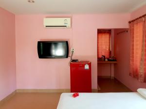 Habitación con nevera roja y TV en la pared. en Wansawang Homestay en Pran Buri