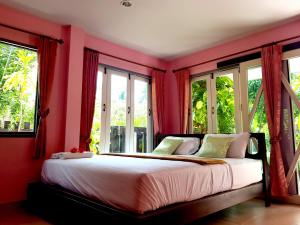 a bedroom with red walls and a bed with windows at Wansawang Homestay in Pran Buri