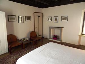 1 dormitorio con 1 cama, 2 sillas y chimenea en Antico Borgo Camporeso, en Galbiate