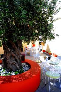 a tree in a red planter next to a table and chairs at Green Garden Studios in Koskinou