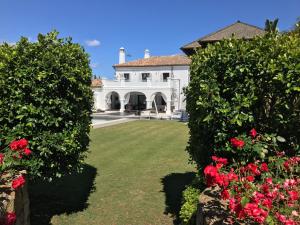 duży biały dom z czerwonymi kwiatami na dziedzińcu w obiekcie Villa Los Halcones Sotogrande Golf w mieście San Roque