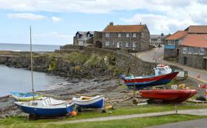 a group of boats sitting on the grass near the water at Craster Crew House in Craster