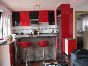 a kitchen with red cabinets and two red bar stools at Piso en Gijon cerca de PLAYA del ARBEYAL in Gijón
