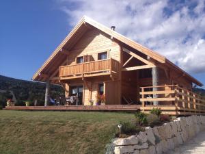 a large wooden house with a balcony on a hill at Au cœur du bois in Le Bouilly