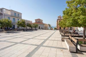 a street with benches and trees and buildings at B&B Bianco E Blu in Marina di Ragusa