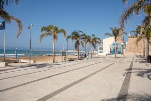 una playa de arena con palmeras y el océano en B&B Bianco E Blu en Marina di Ragusa