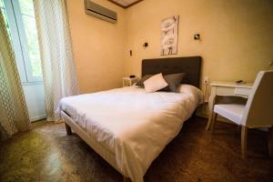 a bedroom with a bed and a desk and a window at Logis hôtel restaurant de Provence in Orange
