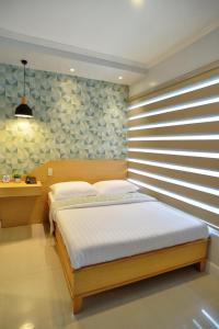 a bedroom with a bed with a wooden headboard at Hotel Formosa Daet in Daet