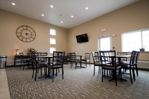 ein Zimmer mit Tischen und Stühlen und einer Uhr an der Wand in der Unterkunft Cornerstone Inn & Suites Oelwein in Oelwein