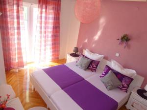1 dormitorio con cama morada y blanca con almohadas en Apartments Veronika, en Makarska
