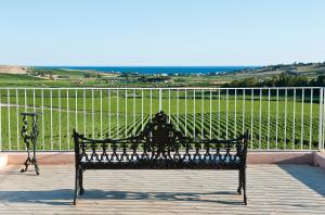 a black bench sitting on a balcony with a view at La Foresteria Planeta Wine Resort & Beach Club in Menfi