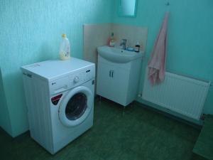 eine Waschküche mit einer Waschmaschine und einem Waschbecken in der Unterkunft Дом на Одесской ул. in Tschornomorsk