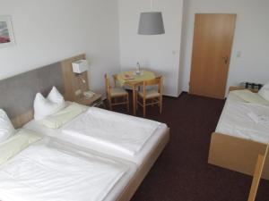 a hotel room with two beds and a table at Hotel Reuterhof in Reuterstadt Stavenhagen