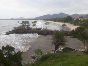 vistas a una playa con palmeras y al océano en Chales Ubatuba I, en Ubatuba