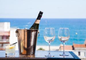 Apartment Beach Front Canet في كانيه دي مار: زجاجة من النبيذ في دلو بجوار كأسين من النبيذ