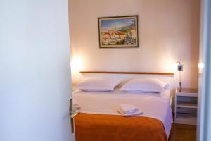 1 dormitorio con 1 cama con sábanas y almohadas blancas en Apartments Klarić en Makarska