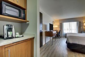 a hotel room with a bed and a kitchen with a microwave at Holiday Inn & Suites Peoria at Grand Prairie, an IHG Hotel in Peoria