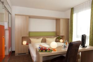 a bedroom with a bed and a table with fruit on it at Hotel AVIVA by APOLONIA in Karlsruhe