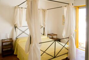 a bedroom with a four poster bed with white curtains at Casa la Mimosa in Leuca