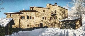 a large stone building with snow in front of it at B&B Ca Dei Lenzotti in Riolunato