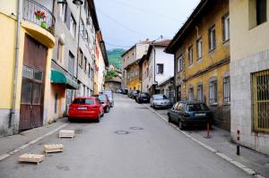 una calle de la ciudad con coches estacionados al costado de la carretera en Dino en Sarajevo