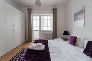 a bedroom with a large white bed with purple accents at The Arc Residence in Astana