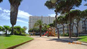 un parc avec une aire de jeux bordée de palmiers et un bâtiment dans l'établissement Apartament La Vista Bonica, à Blanes
