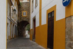 
a narrow alleyway leads to a building with a clock on it at Casa do Arco Portalegre in Portalegre
