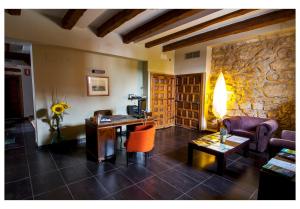 sala de estar con escritorio y pared de piedra en Posada La Casona de Valbuena en Valbuena de Duero