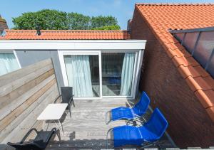 um pátio com cadeiras azuis, uma mesa e uma mesa branca em Holiday Home Zuidstraat 30B em Westkapelle