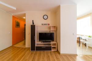 a living room with a television and a wall with a clock at Apart-Comfort Dresden in Yaroslavl