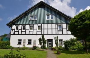 a white and black house with a green roof at Feldmann-Schütte in Schmallenberg