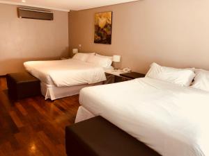 a hotel room with two beds and a desk at San Isidro Plaza Hotel in San Isidro