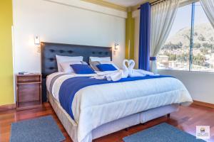 Schlafzimmer mit einem Bett mit blauer und weißer Bettwäsche und einem Fenster in der Unterkunft Hotel Lago Azul in Copacabana