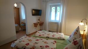 a bedroom with a bed and a tv and windows at Mühldorfer Hof in Altötting