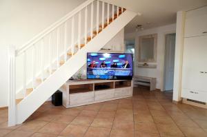 a living room with a tv under a staircase at Haus Wyden in Utersum