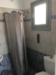 a bathroom with a shower and a toilet and a window at Camares in Chora Folegandros