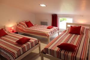 a room with three beds with red pillows on them at A chacun son nid in Les Épesses