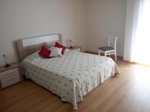 a bedroom with a white bed with red pillows and a chair at Fun & Sun Apartment in Olhão