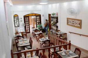 a restaurant with tables and a person standing in a room at Pousada Luar da Serra in Conservatória