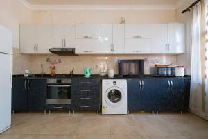a kitchen with white cabinets and a washing machine at Sunny Hotel Batumi in Makhinjauri