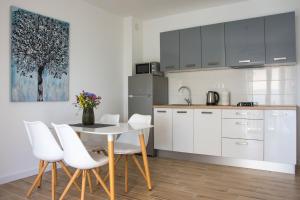 a kitchen with white cabinets and a table and chairs at Apartments Melody in Mandre