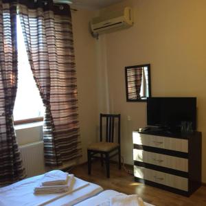 Un dormitorio con una cama y una cómoda con televisión. en Amigos, en Pawlikeni