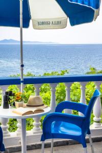 een tafel en stoelen op een balkon met uitzicht op de oceaan bij Villa George in Batsi