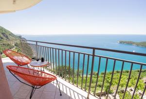 een balkon met rode stoelen en uitzicht op de oceaan bij Apartments Villa Vanja in Budva