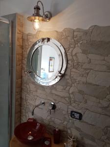 y baño con lavabo y espejo en una pared de piedra. en B&B Cara'a mare, en Santa Maria Navarrese