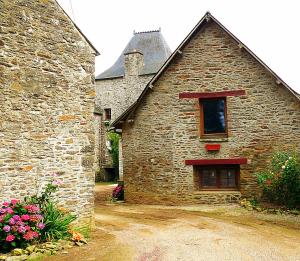 an old stone building with a window and flowers at Manoir du Mur in Comblessac