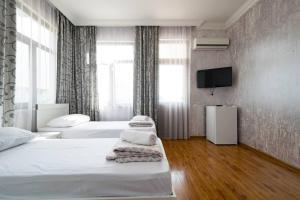a hotel room with two beds and a flat screen tv at Sunny Hotel Batumi in Makhinjauri