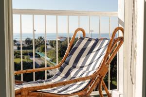 una sedia a dondolo su un balcone con vista sull'oceano di Elegante Attico panoramico a 2 passi dal mare a Forte dei Marmi