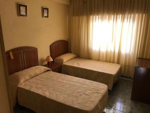 a hotel room with two beds and a window at Piso ideal para las vacaciones in Miramar
